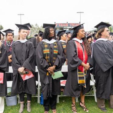 Graduates standing together watching the podium