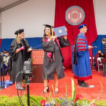 A graduate on stage holding a diploma