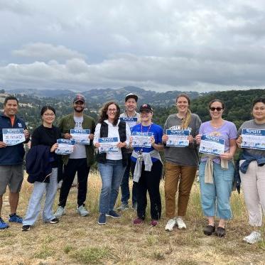 Picture of 9 people holding Step Up signs at top of the cross to honor veterans